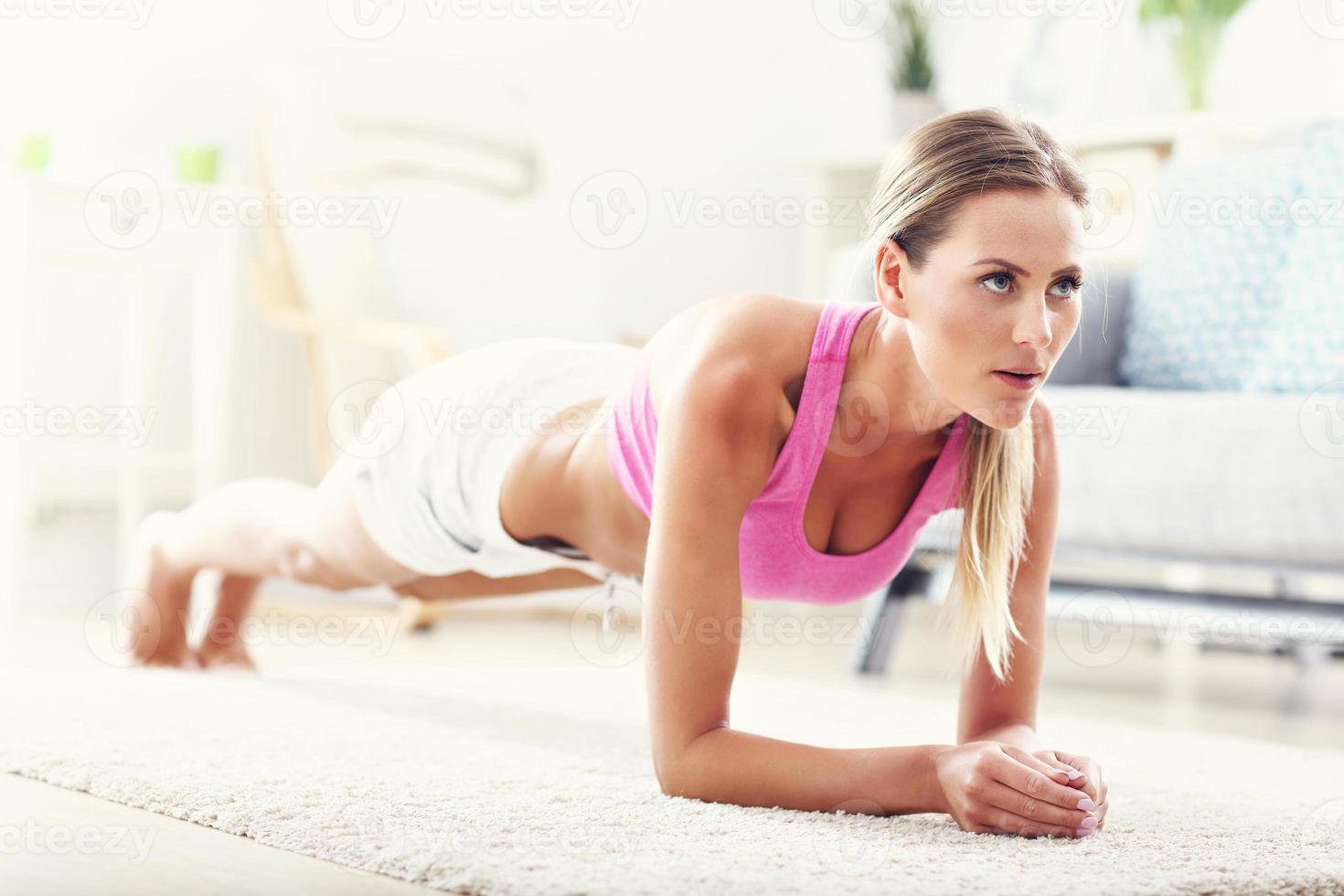 Fit girl in plank position at home in the living room photo