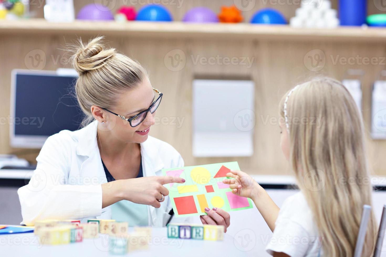 Child psychologist working with young girl in office photo