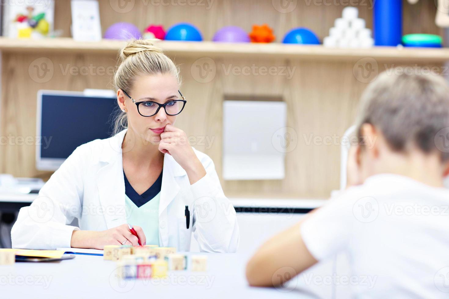 Child psychologist working with young boy in office photo