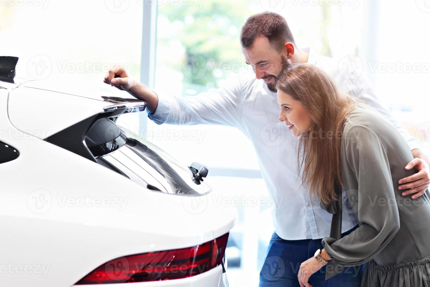 pareja adulta eligiendo auto nuevo en la sala de exposición foto