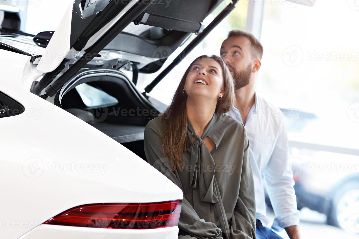 Adult couple choosing new car in showroom photo