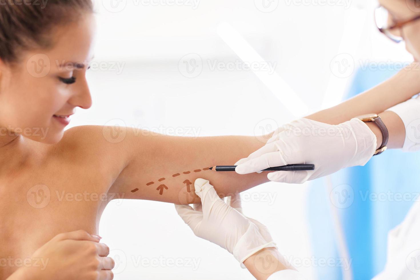 Plastic surgeon making marks on patient's body photo