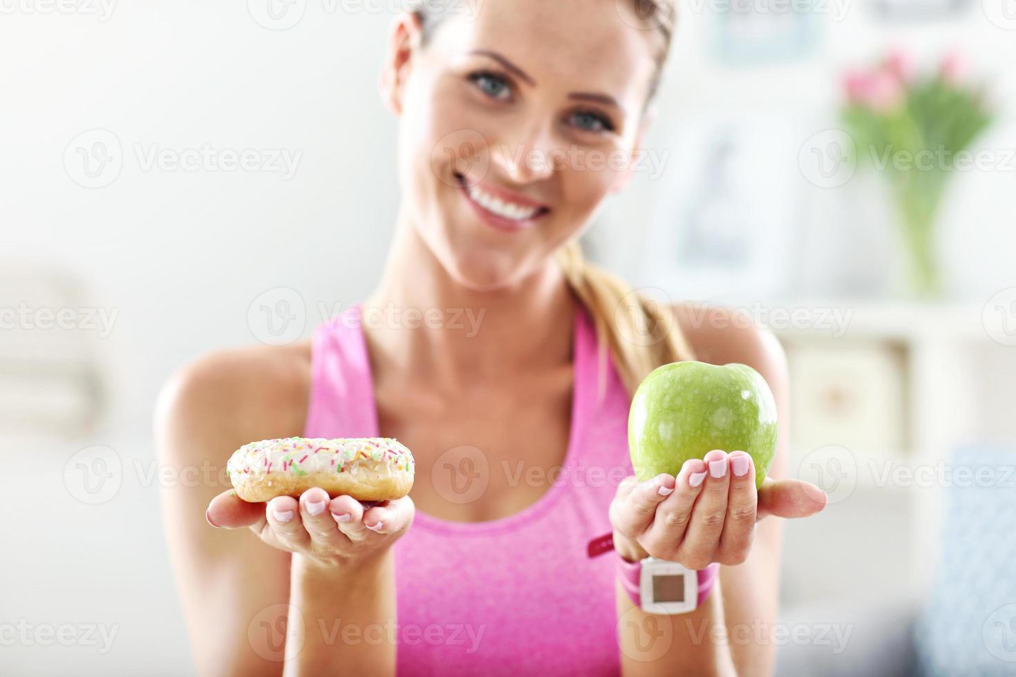 Sporty woman with apple and donut after workout photo