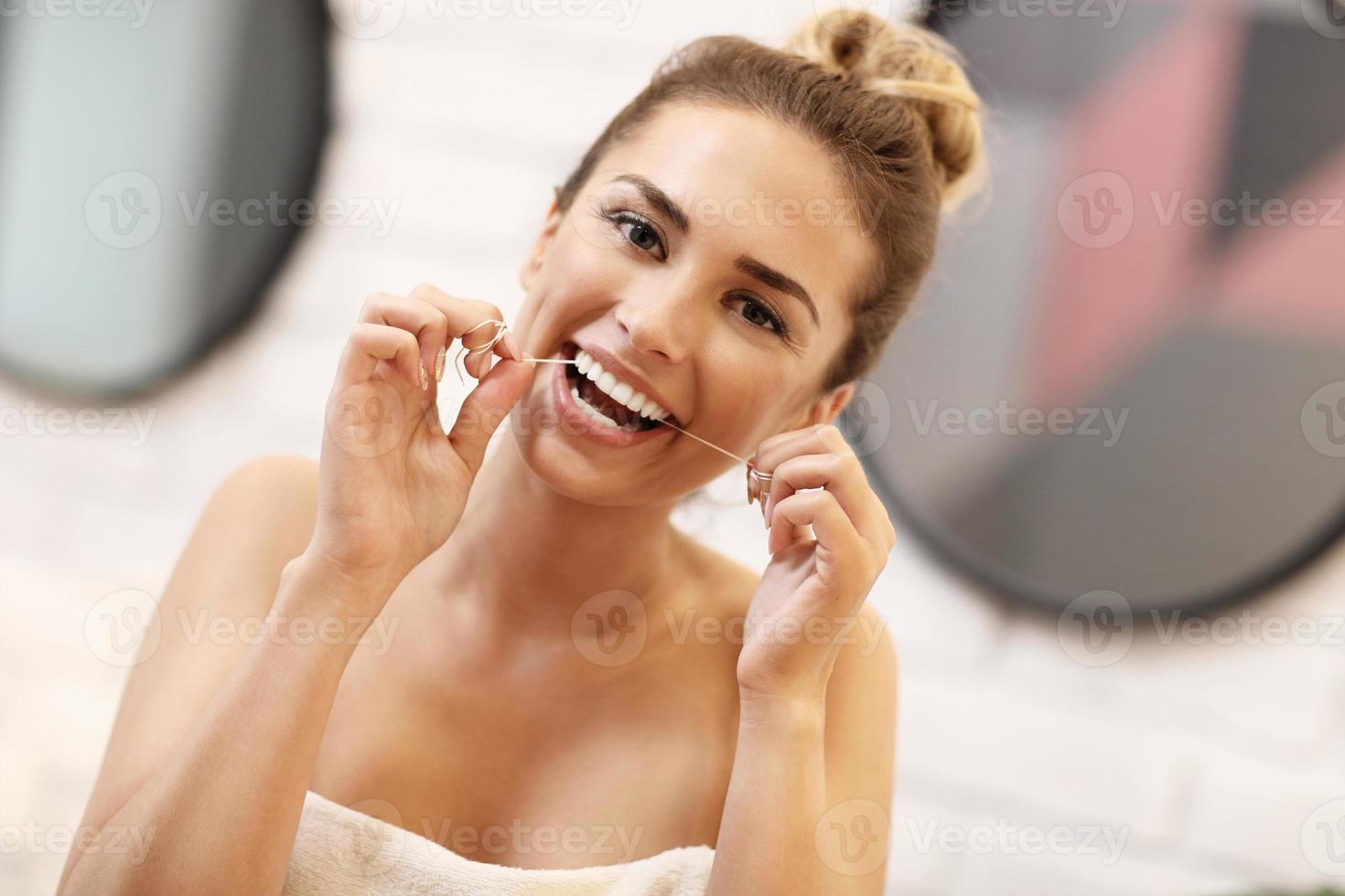 mujer joven cepillarse los dientes en el baño foto