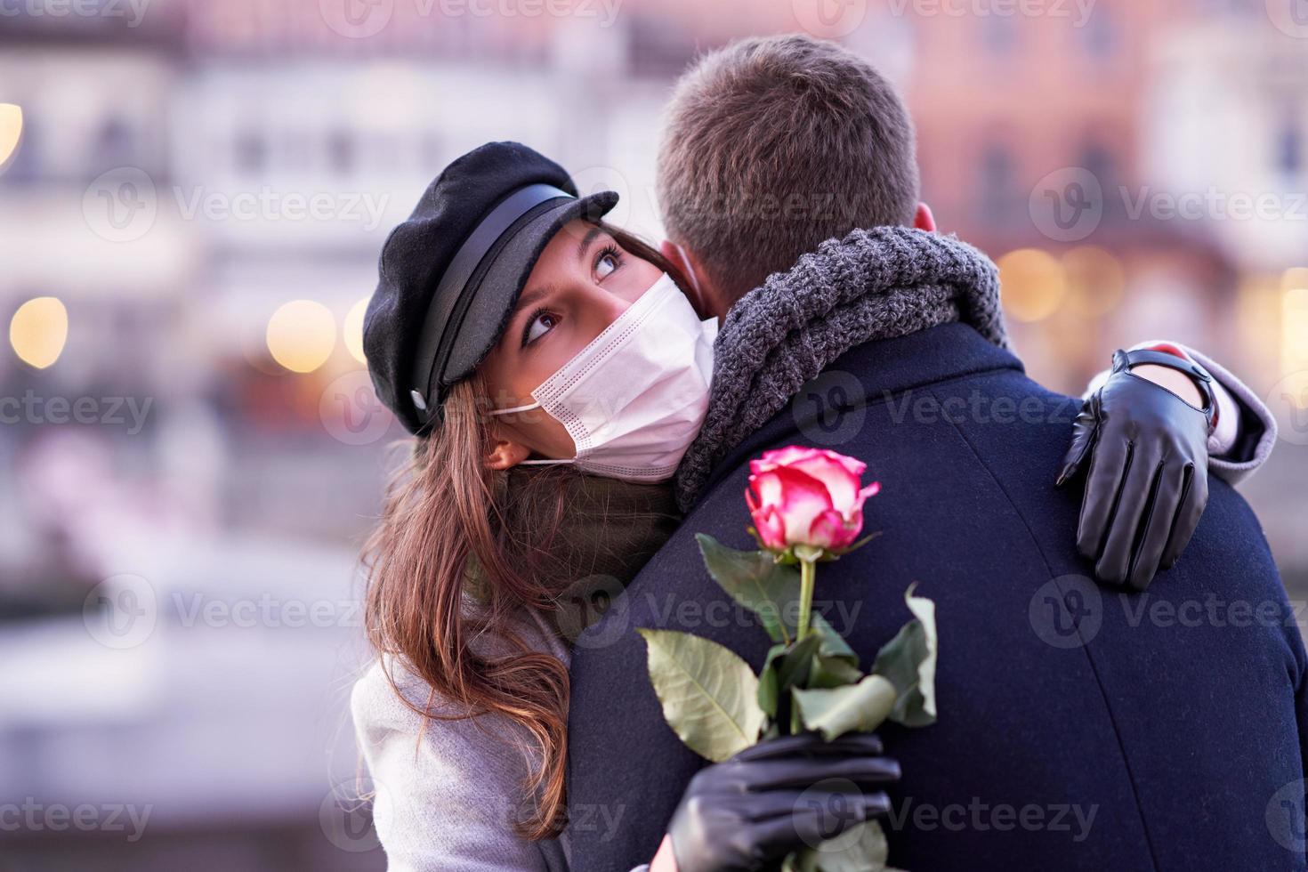 Happy couple celebrating Valentines Day in masks during covid-19 pandemic photo