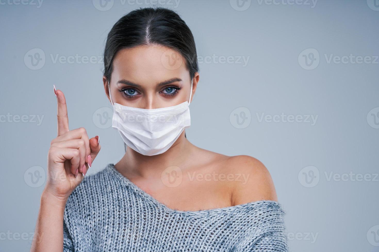 Portrait of beautiful woman in mask on gray background photo