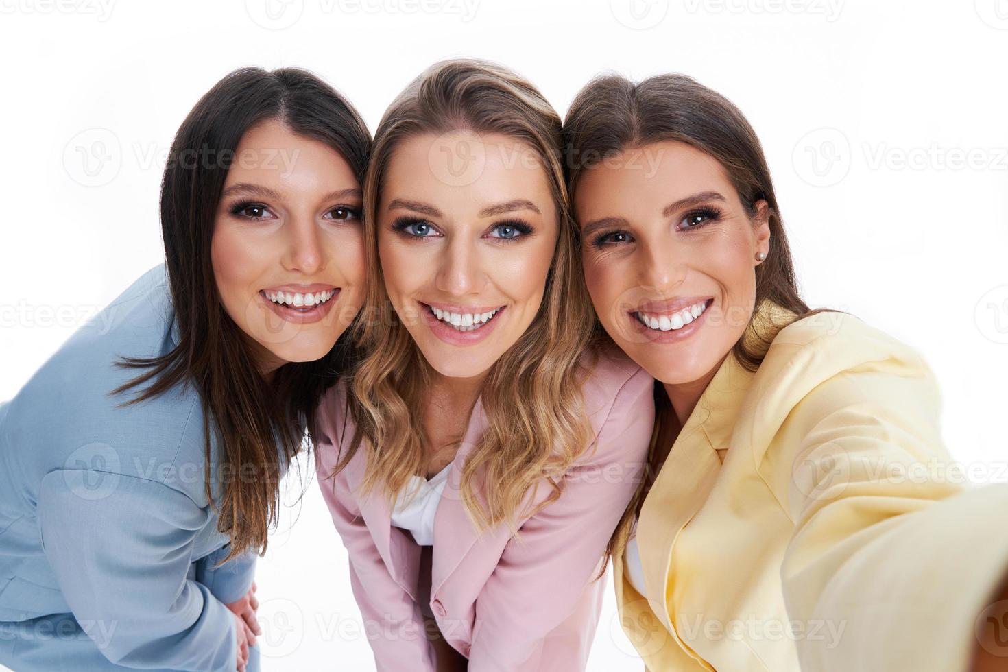 Three women in pastel suits posing over white background photo