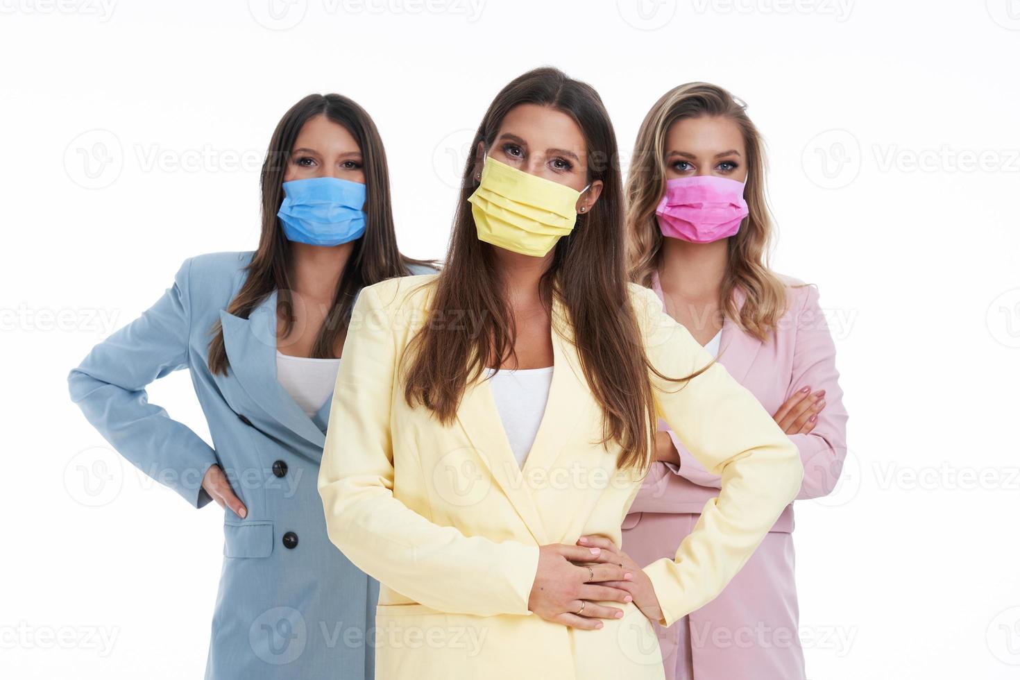 Three women in pastel suits posing over white background photo