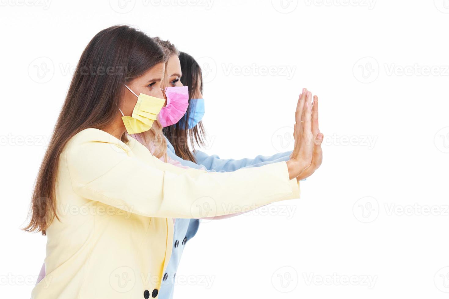 Three women in pastel suits posing over white background photo