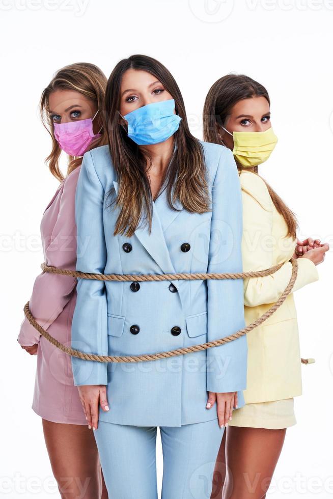 Three women in pastel suits posing over white background photo