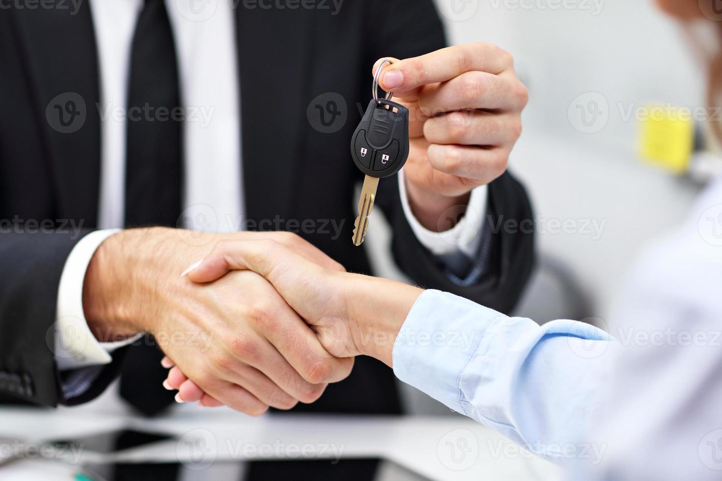 Midsection of businesspeople shaking hands and giving key photo