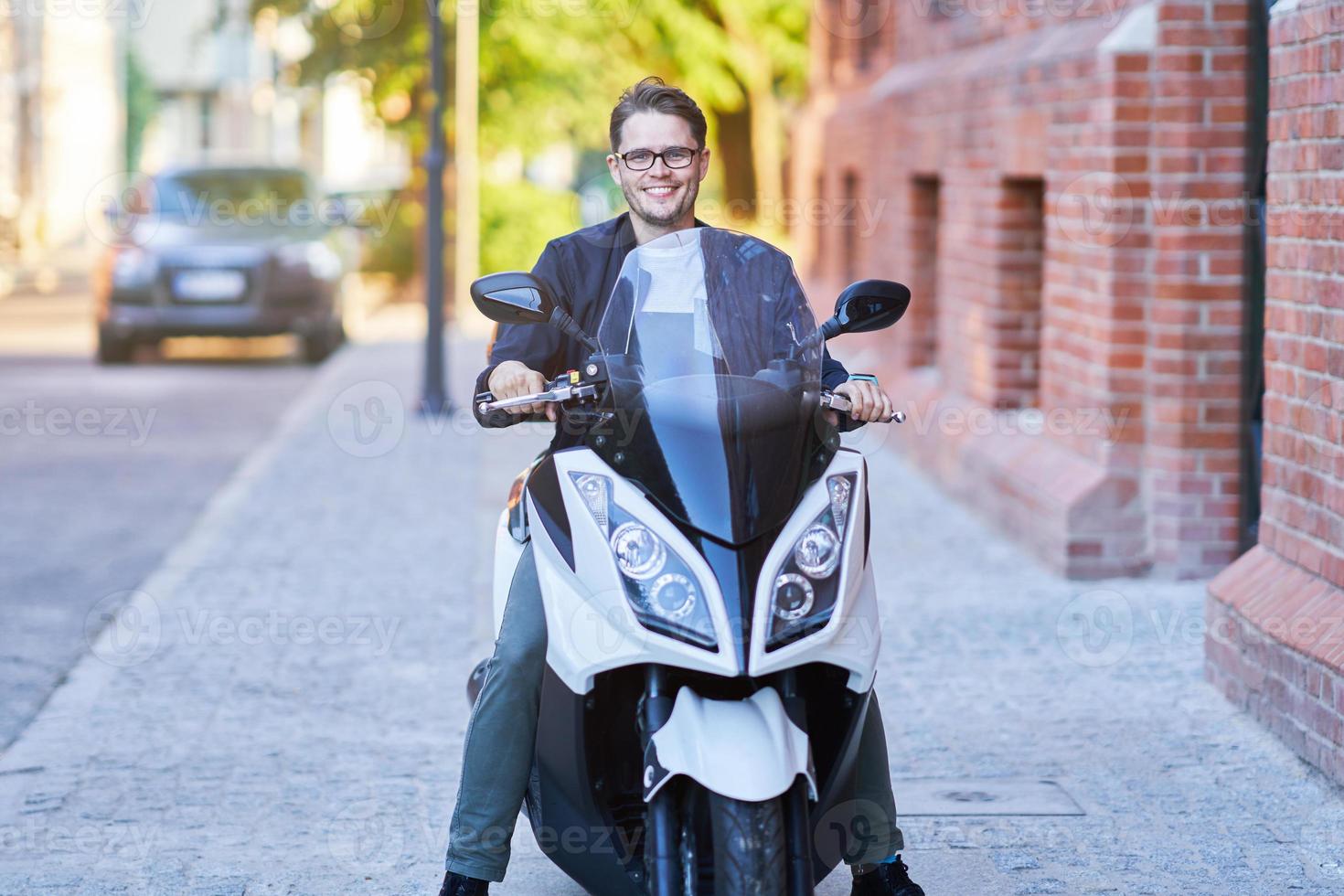 Happy man riding a scooter in the city on a sunny day photo