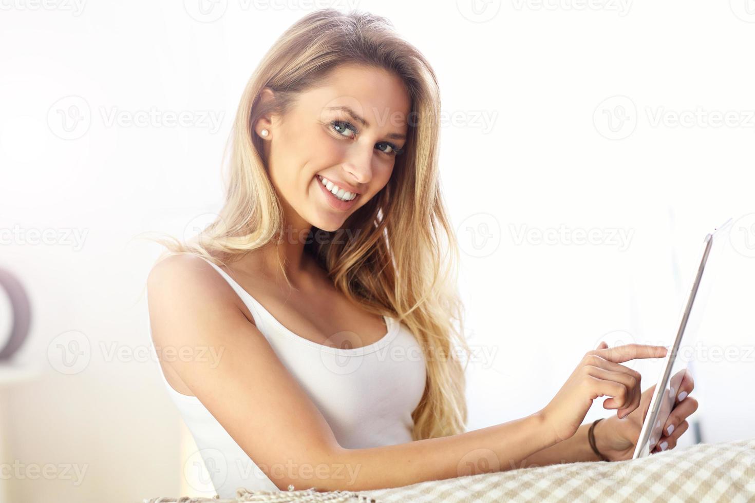 Happy woman with tablet on sofa photo