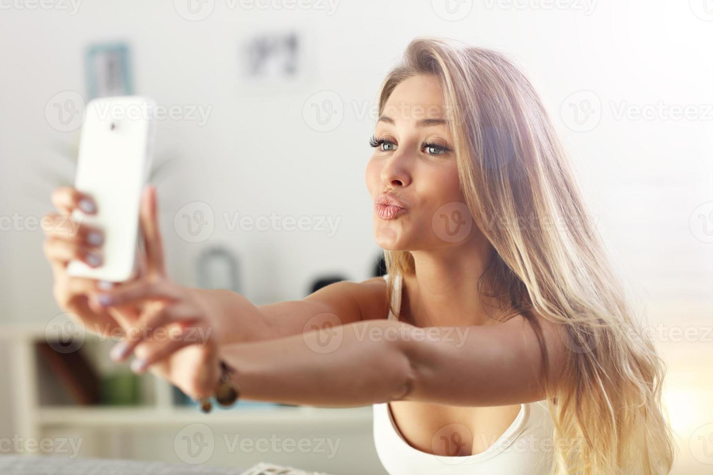 mujer feliz tomando selfie en el sofá foto
