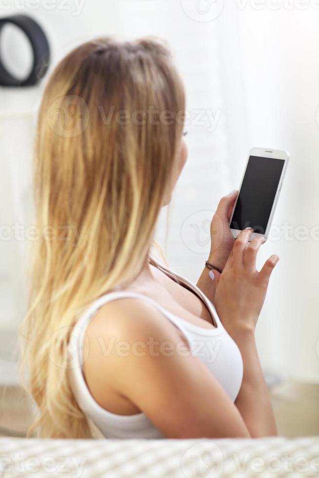 mujer feliz con teléfono inteligente en el sofá foto
