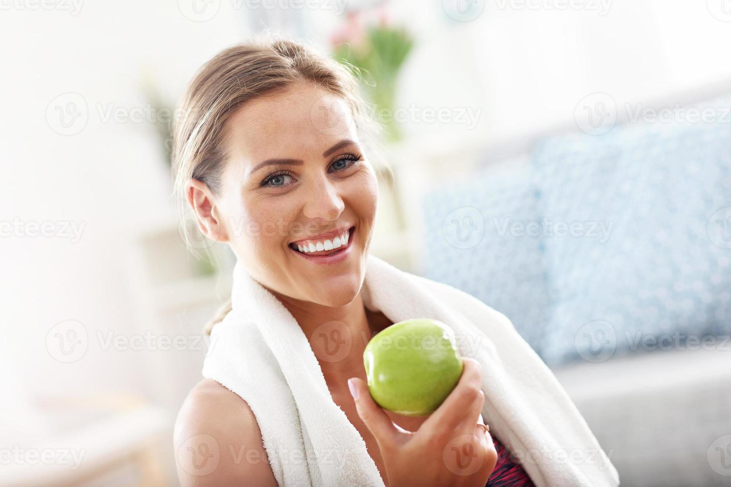 Fit woman eating carrot at home photo