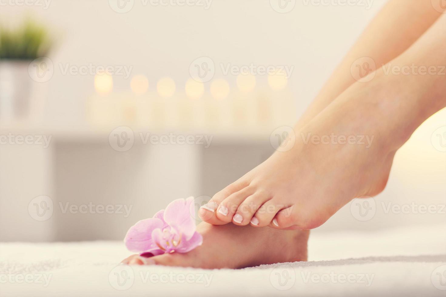 Soft female feet with french pedicure and flowers close up photo