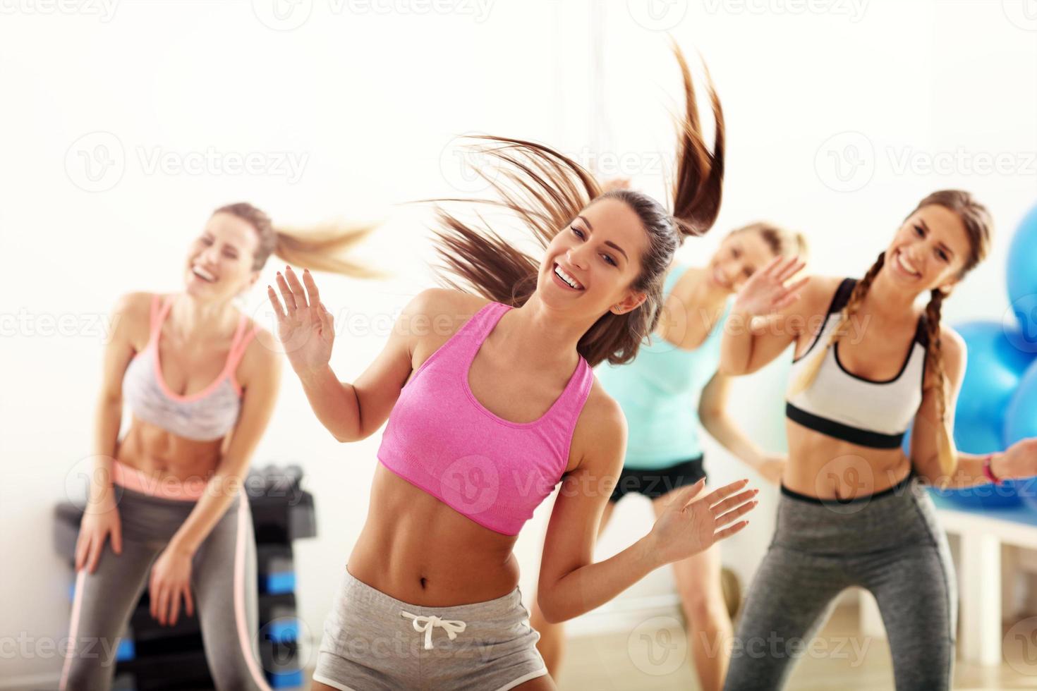 grupo de gente feliz con entrenador bailando en el gimnasio foto