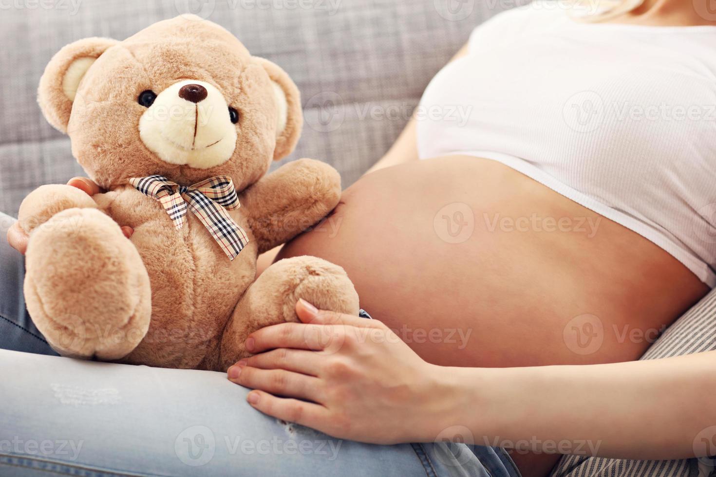 Happy pregnant woman with teddy bear photo