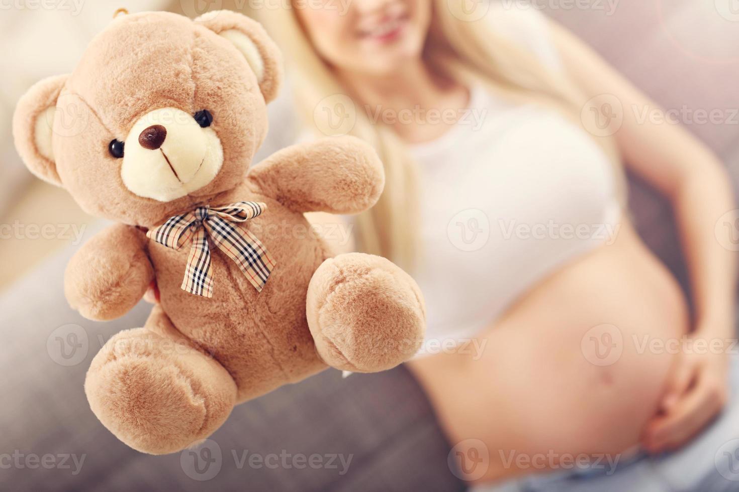 Happy pregnant woman with teddy bear photo