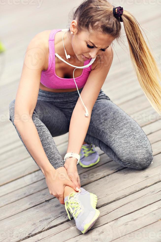 atleta femenina corredora tocando el pie con dolor al aire libre foto