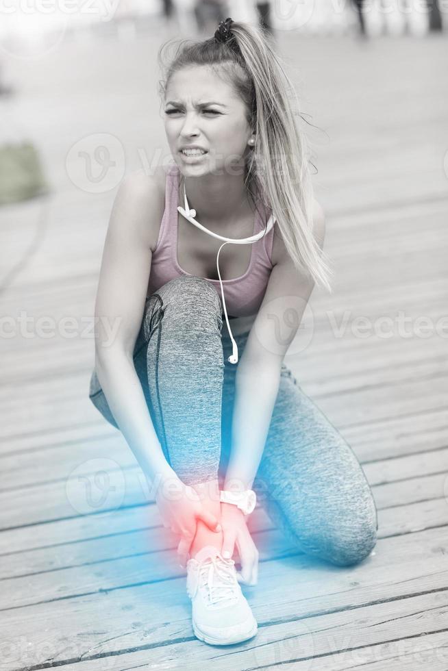 atleta femenina corredora tocando el pie con dolor al aire libre foto