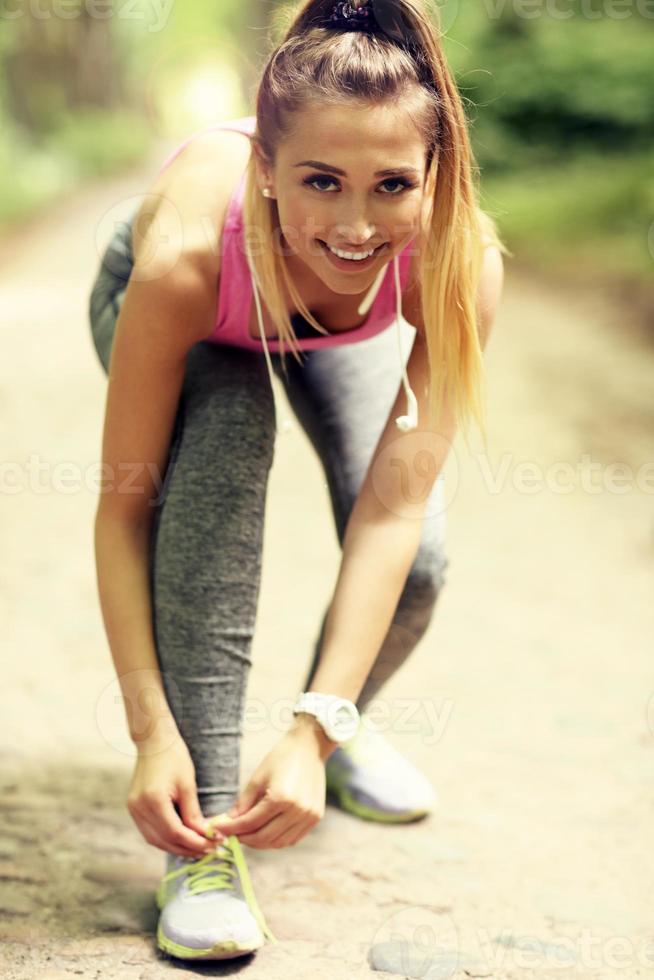 Woman jogging in the forest and tying shoe photo