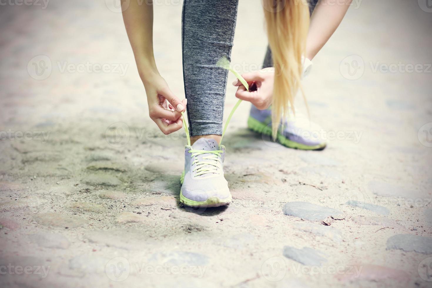 Woman jogging in the forest and tying shoe photo