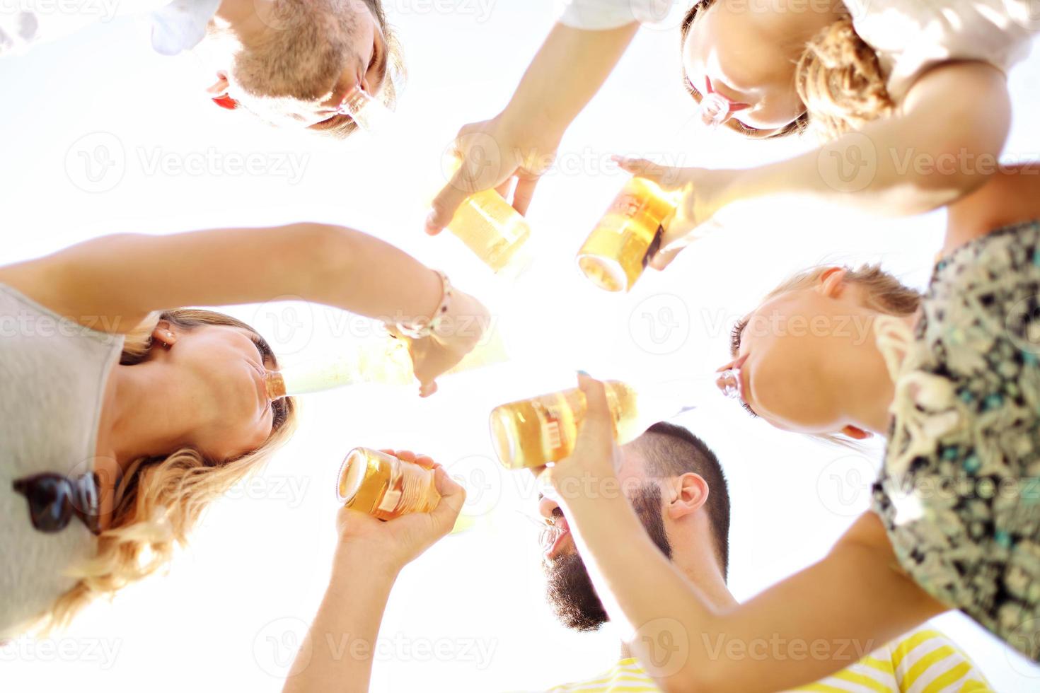 Group of young people cheering and having fun outdoors with drinks photo