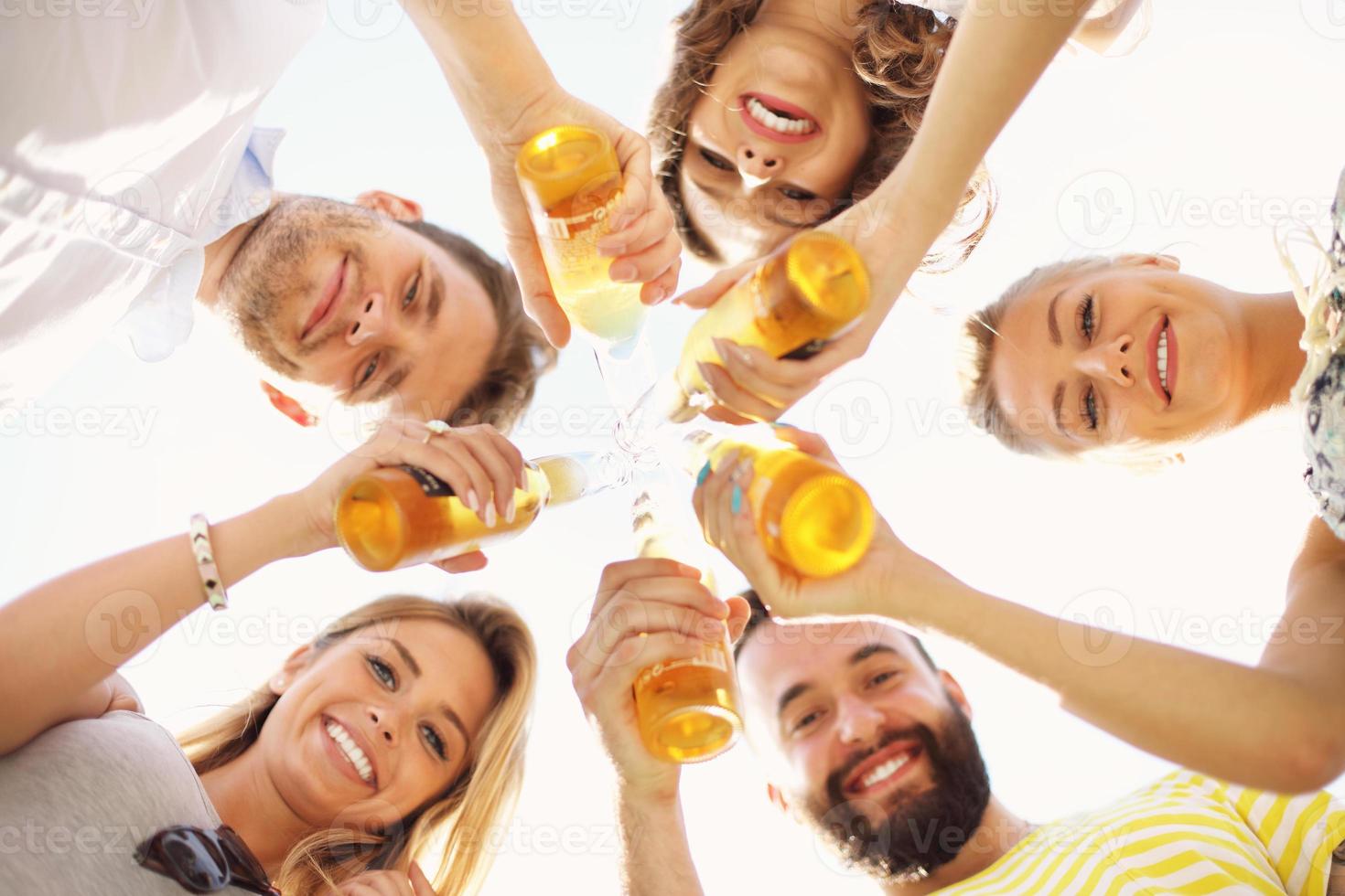 Group of young people cheering and having fun outdoors with drinks photo