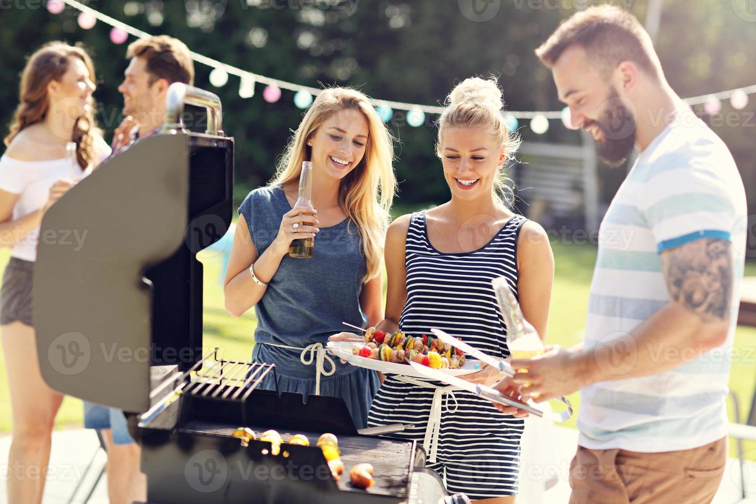 Friends having barbecue party in backyard photo