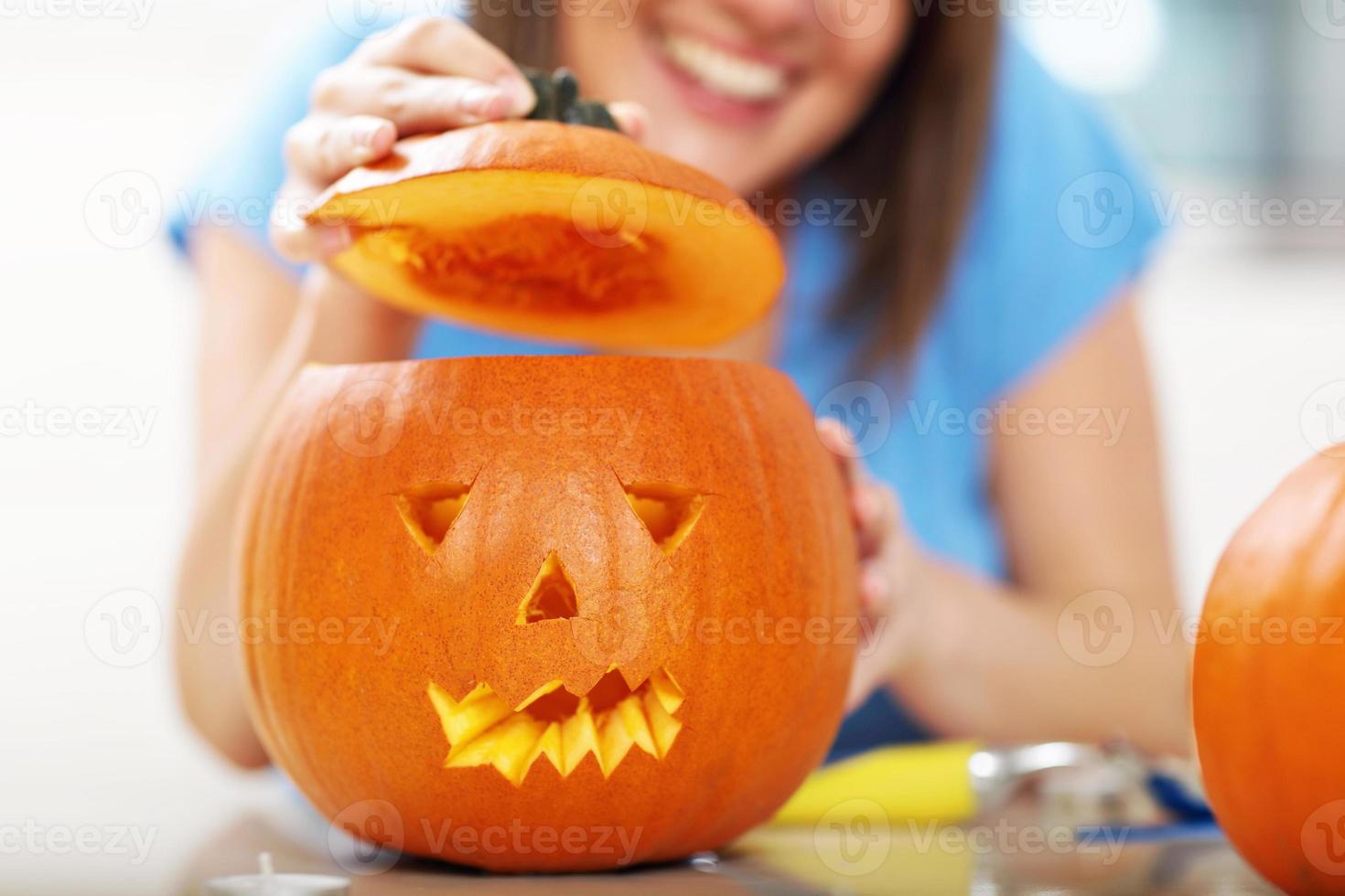 Young woman making jack-o-lantern in the kitchen photo