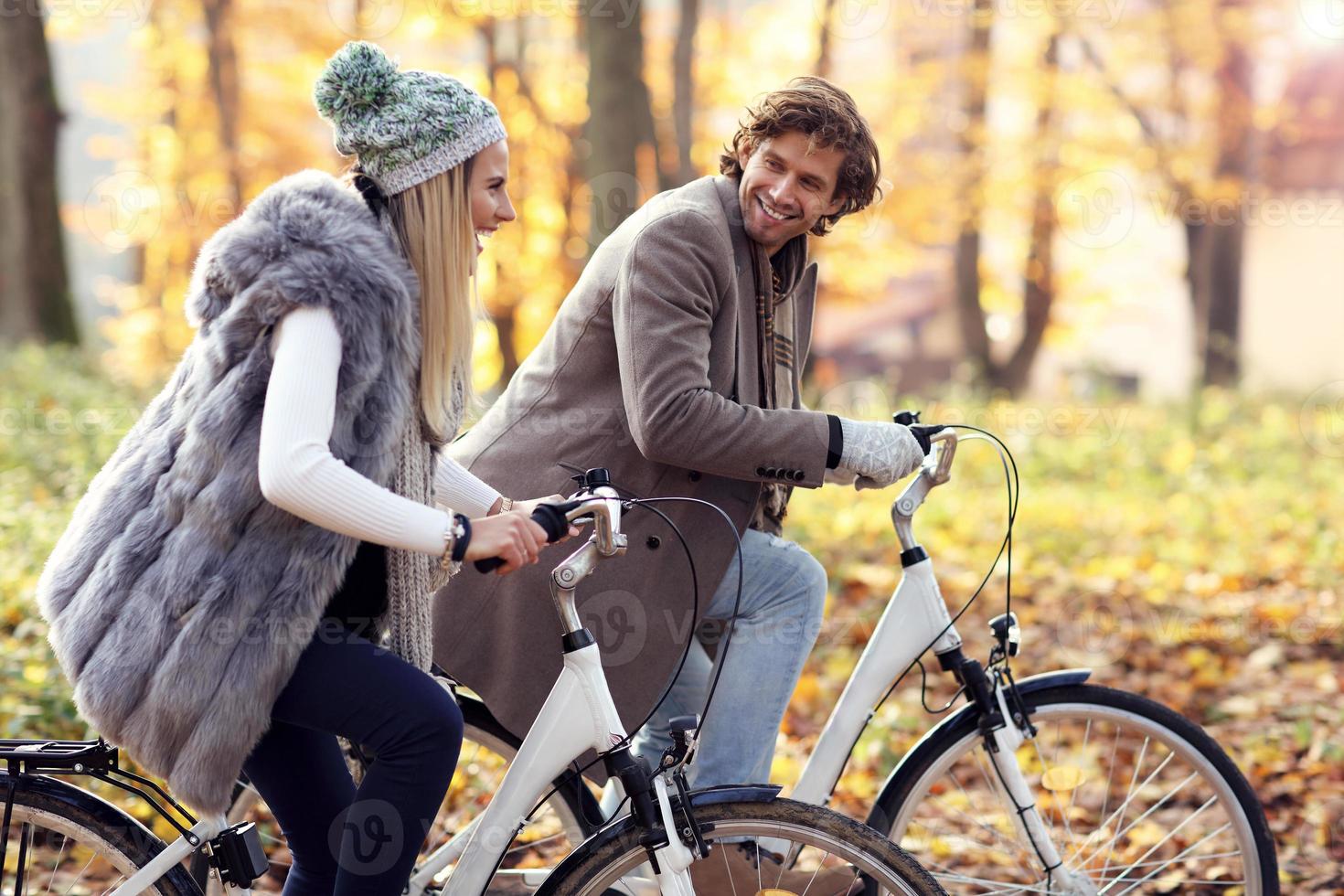 Happy couple on bikes in forest during fall time photo