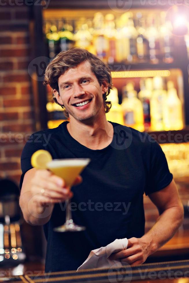 Handsome bartender serving cocktails in a pub photo