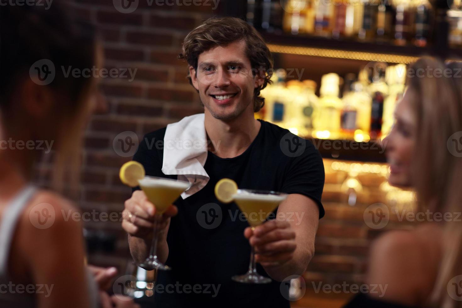 Handsome bartender serving cocktails in a pub photo
