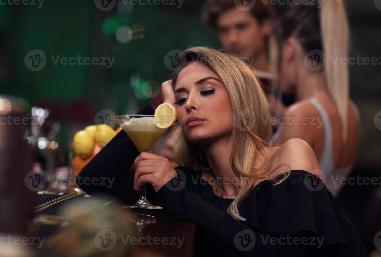 Young woman sitting alone in bar with a coctail photo