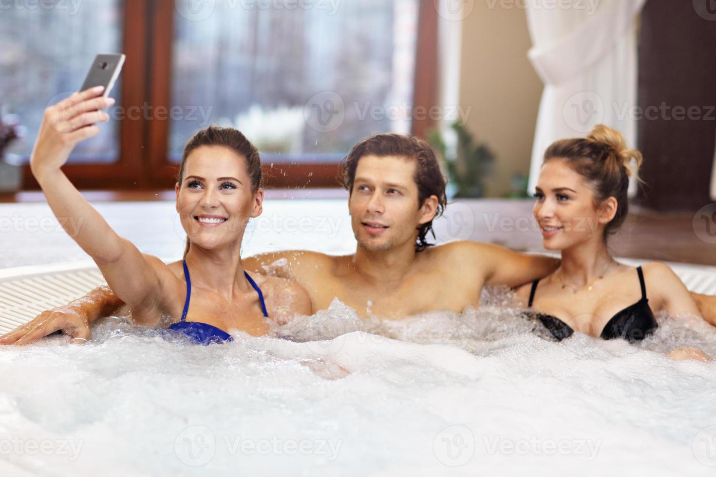Group of friends enjoying jacuzzi in hotel spa photo