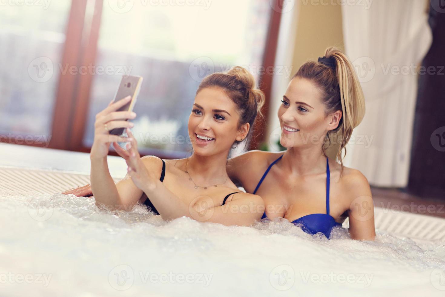 Happy girl friends enjoying jacuzzi in hotel spa photo