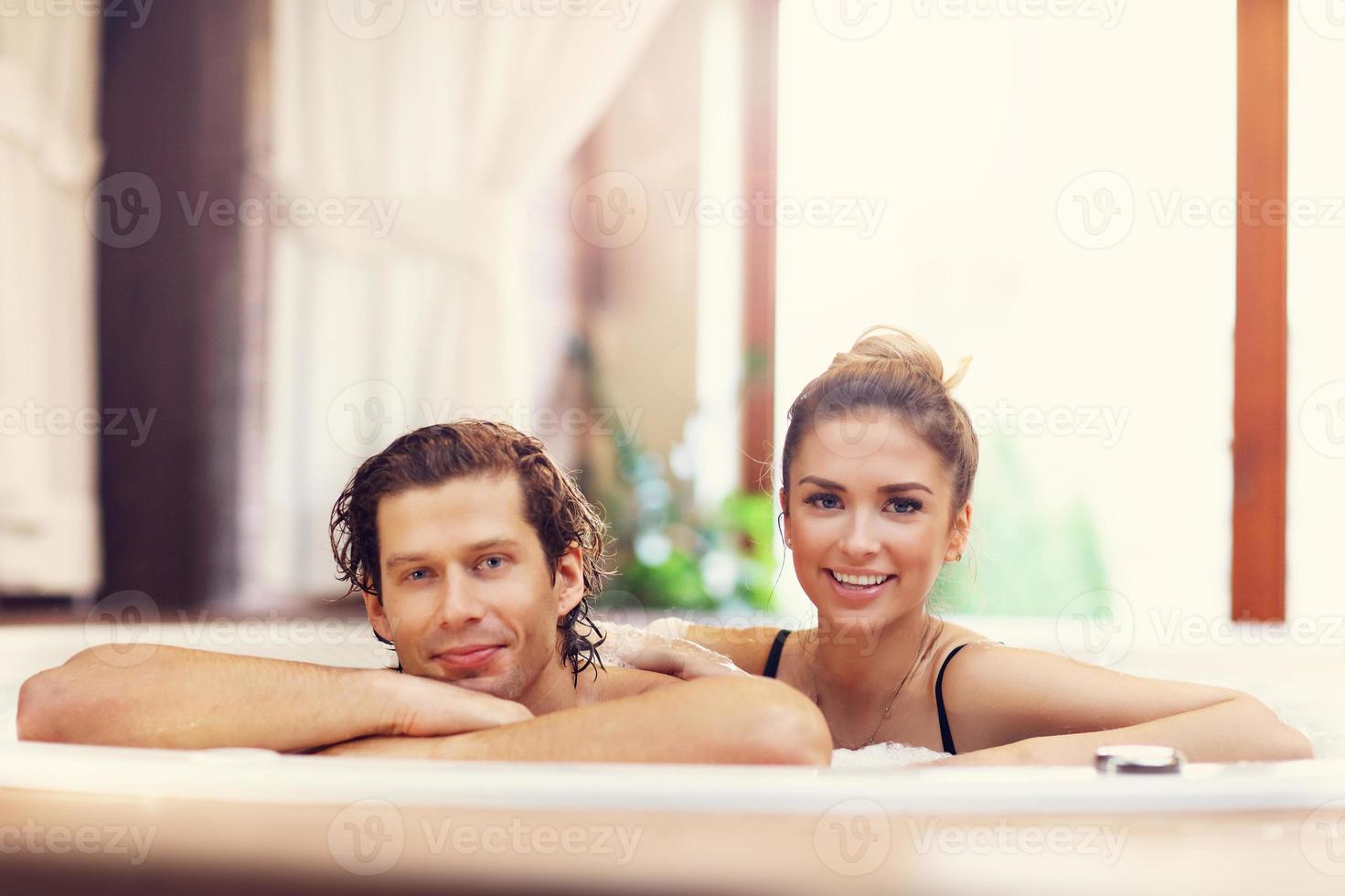 Happy couple enjoying jacuzzi in hotel spa photo