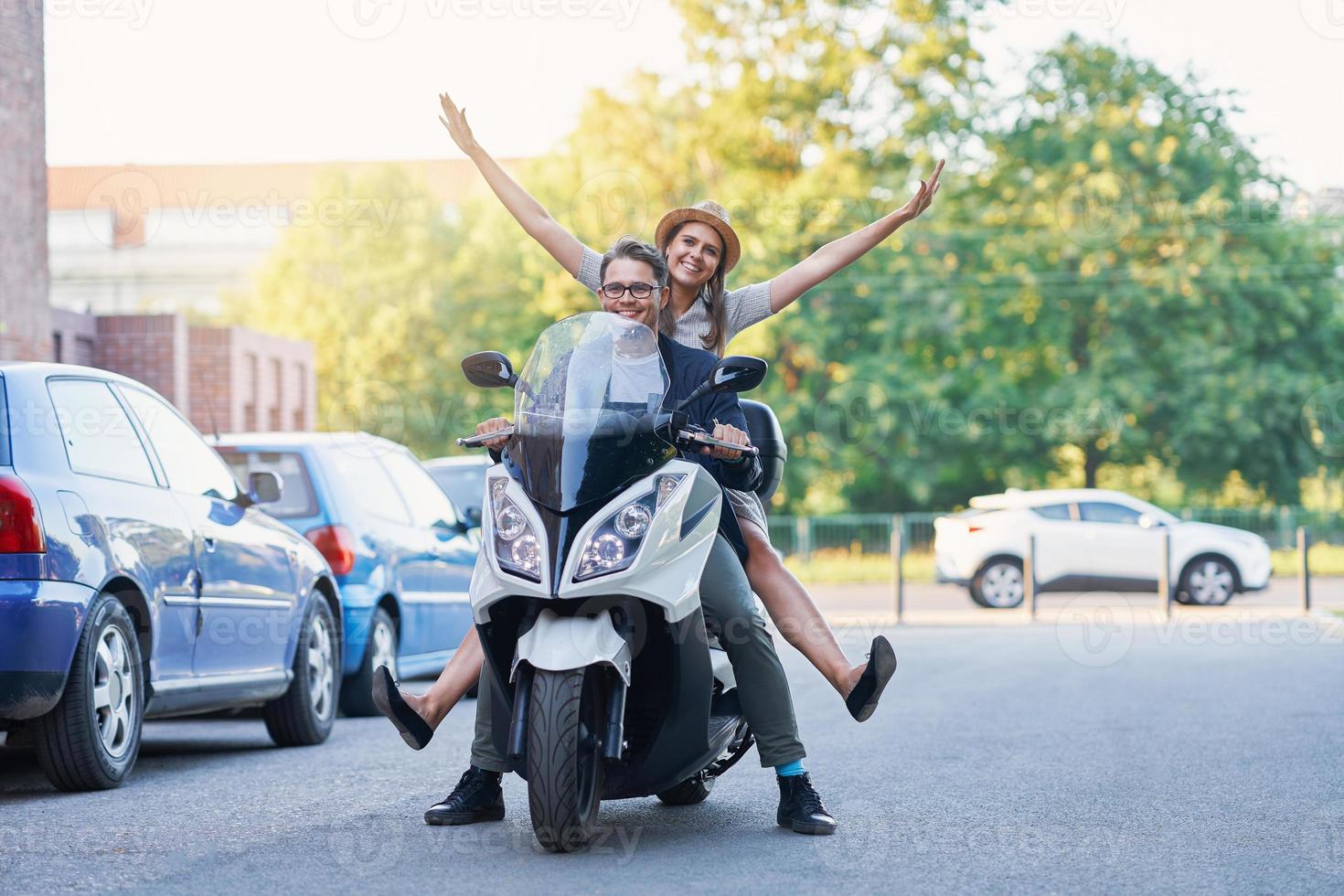 Happy mature couple riding a scooter in the city on a sunny day photo