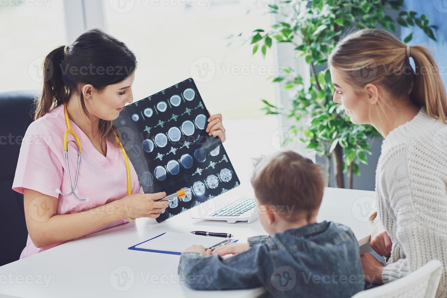 doctor discutiendo los resultados de rayos X con mamá y su hijo foto