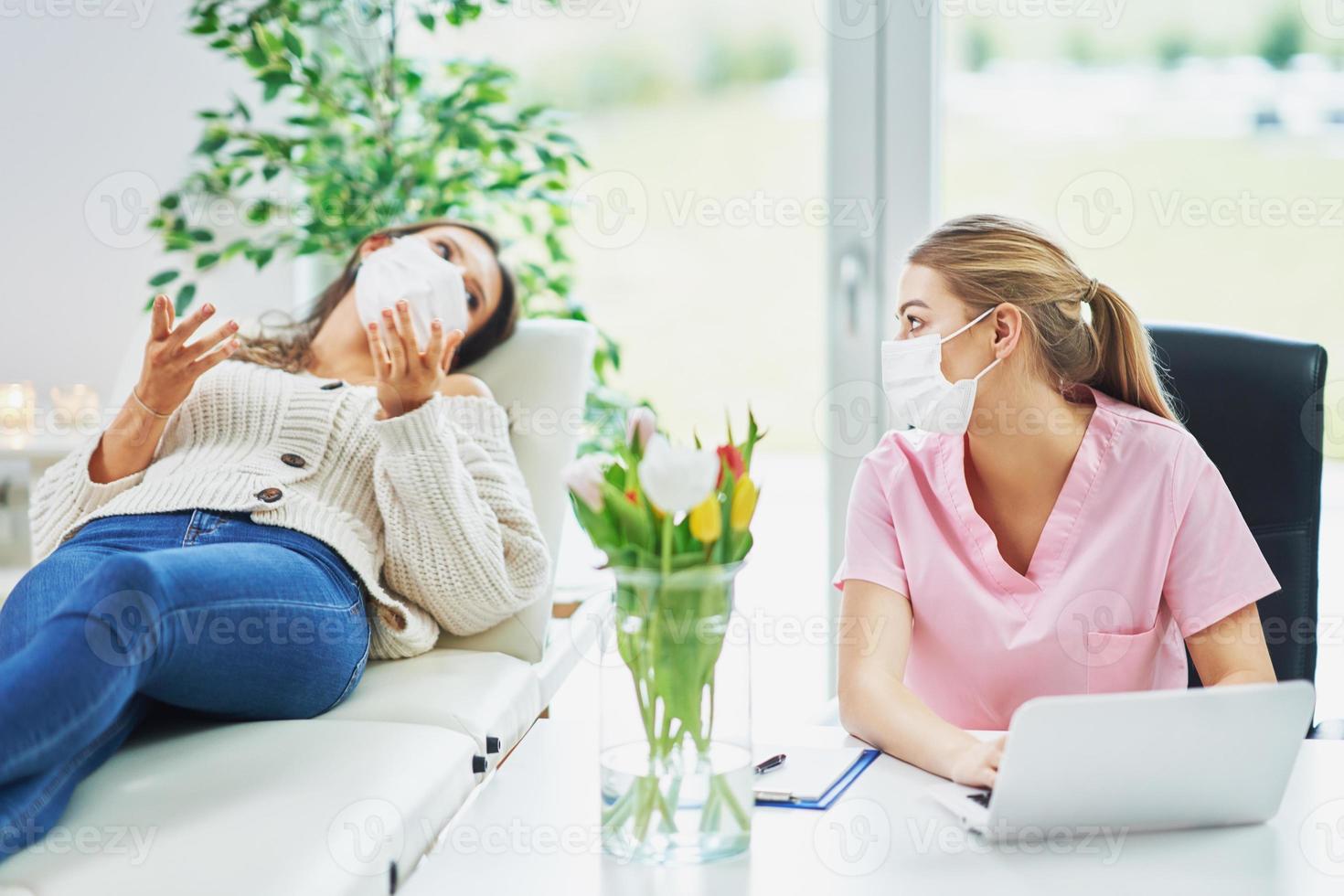 Professional psychiatrist consulting her patient and making notes both in masks photo