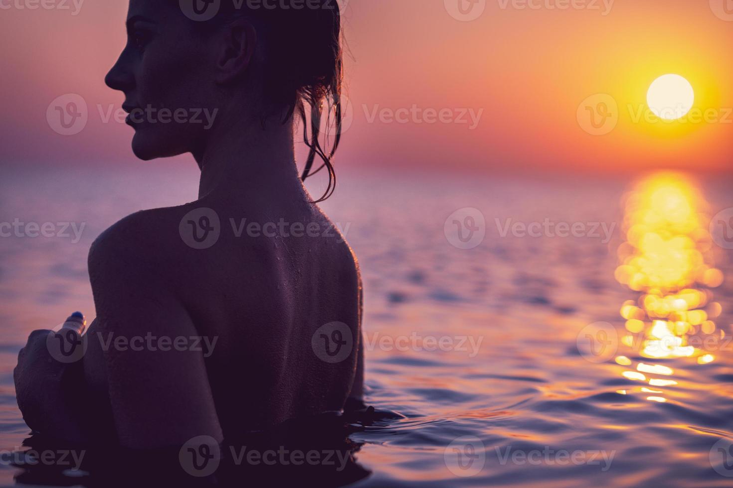 silueta de mujer joven practicando yoga en la playa al amanecer foto