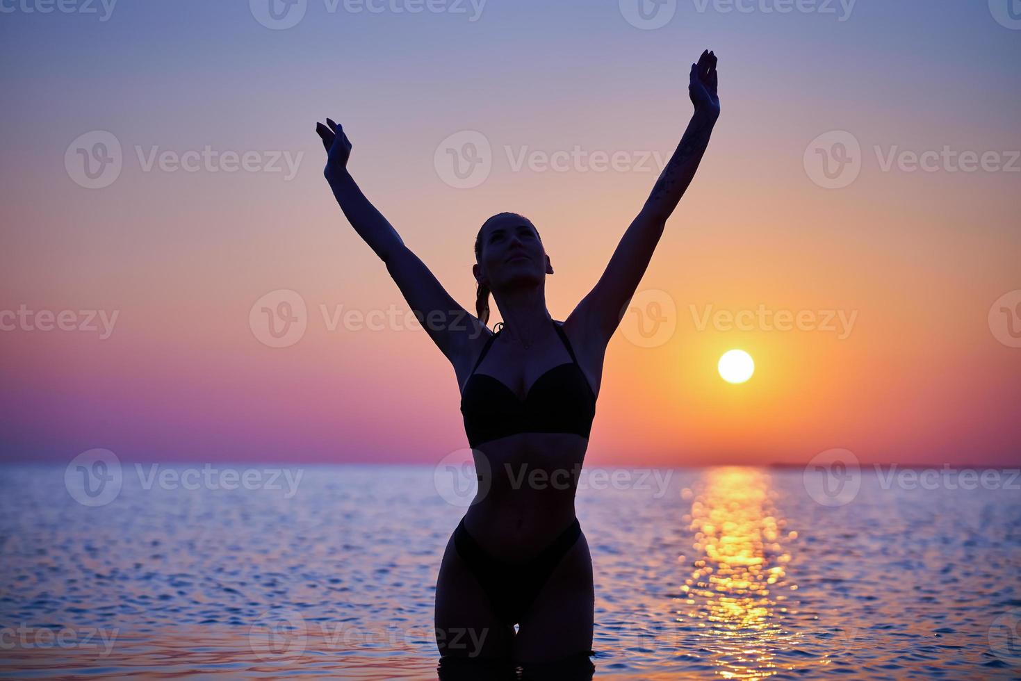 Silhouette of sexy woman posing at sunrise at the beach photo