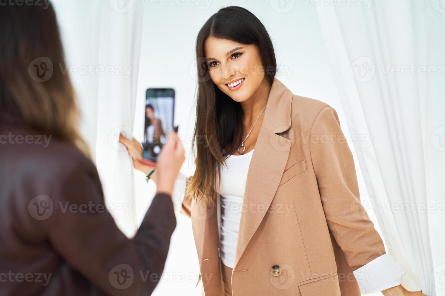 Two girl friends in clothes store in changing room taking selfie photo