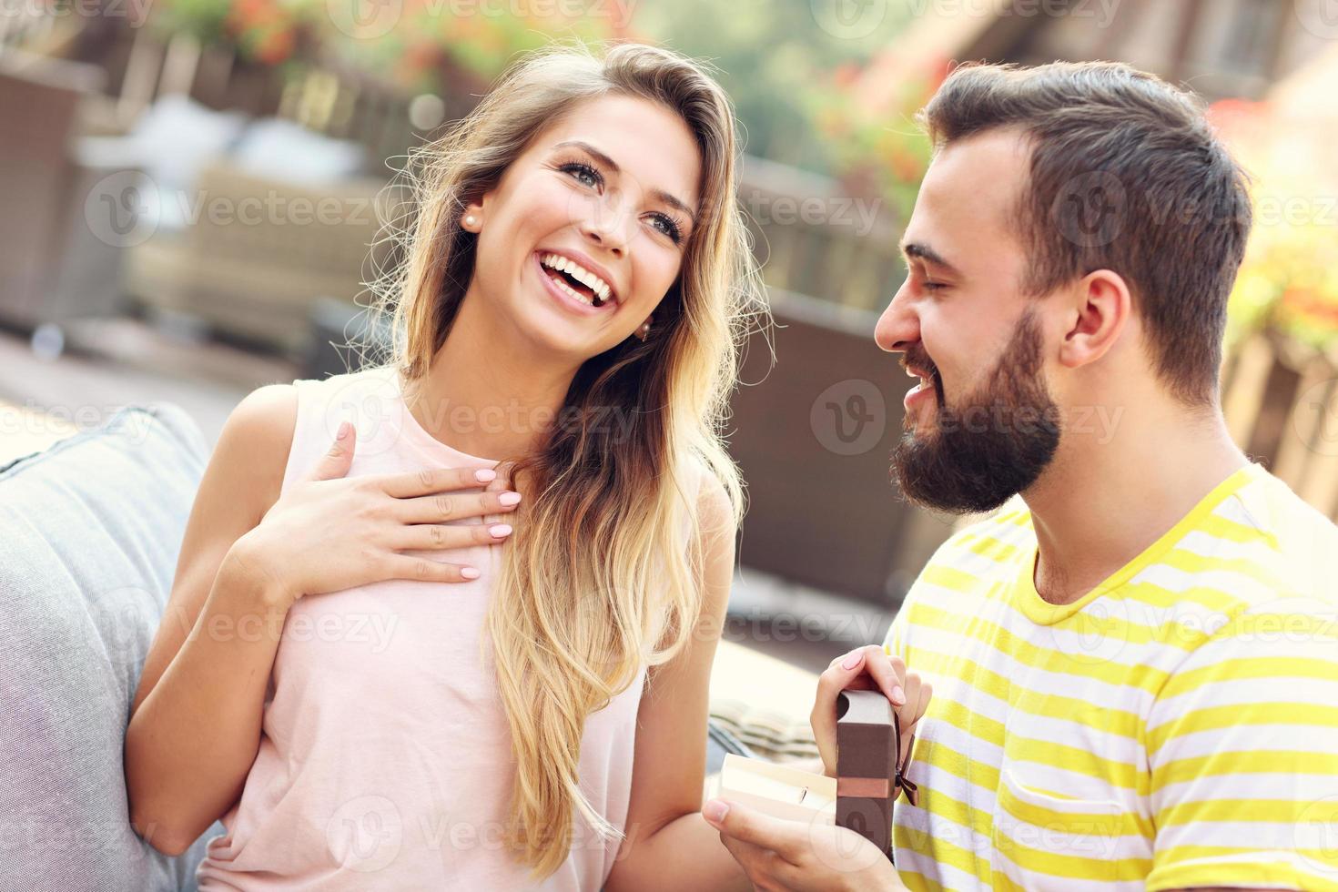 Young man proposing to beautiful woman outdoors photo