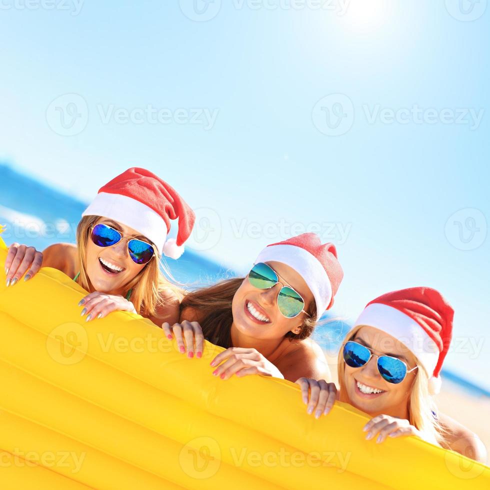 grupo de chicas con sombreros de santa divirtiéndose en la playa foto