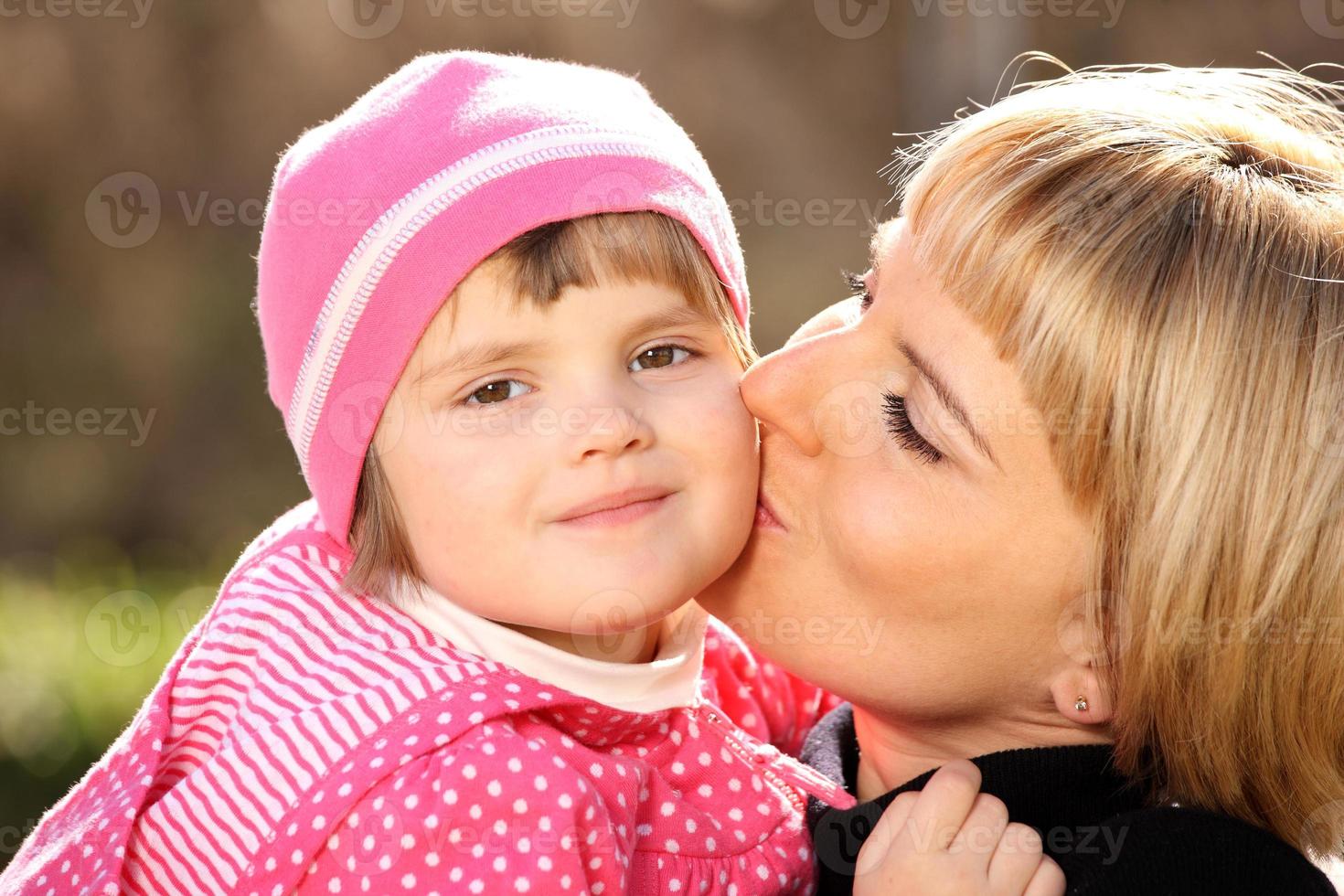 Mother kissing her little girl photo