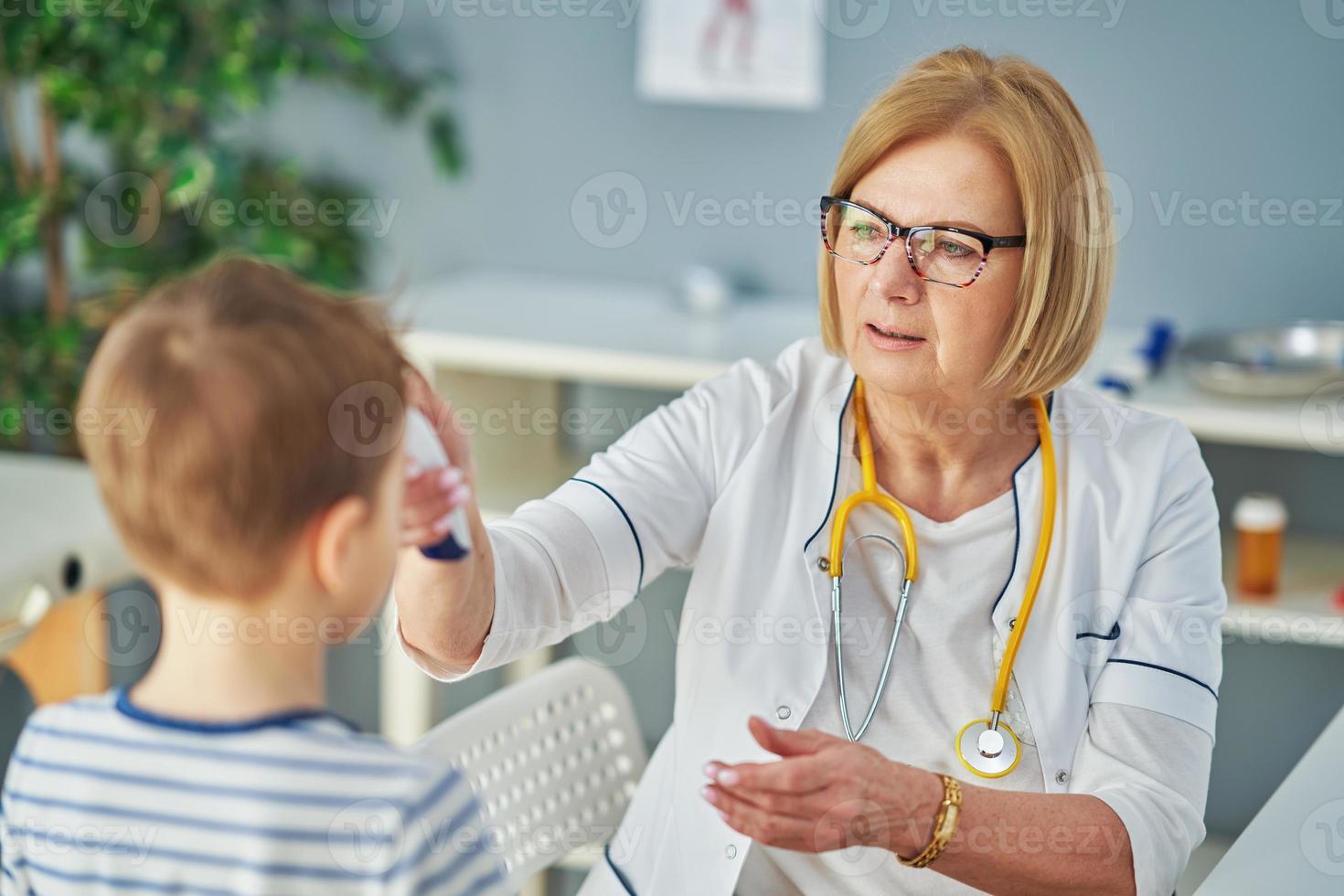 Pediatrician doctor examining little kids in clinic temperature check photo