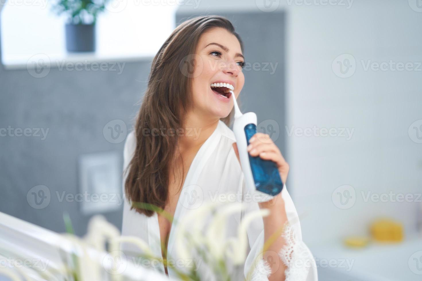 Young nice brunette woman in the bathroom with irrigator photo